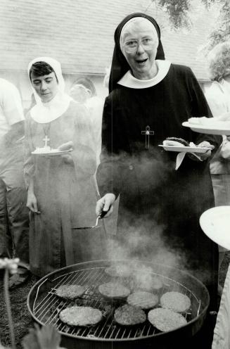 Centennial feast: Sister Ann Mary helps herself to a hamburger while Sister Mary Catherine waits her turn at a barbecue yesterday to wind up the sisterhood's centennial celebrations