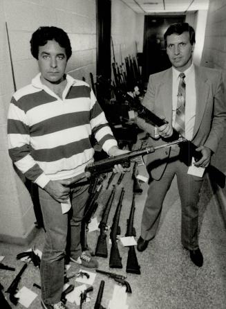 Credit card probe turns up $100,000 arsenal, Detective Fred Tufnell, left, and Detective Jack more hold automatic weapons, part of an arsenal seized M(...)