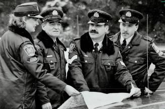 Plan of attack: Auxillary policemen Gai Sims and Charles Knowles, Peel Regional Police sergeant John Rocha, and Dean McCoy check their bearings while organizing a search for a missing person