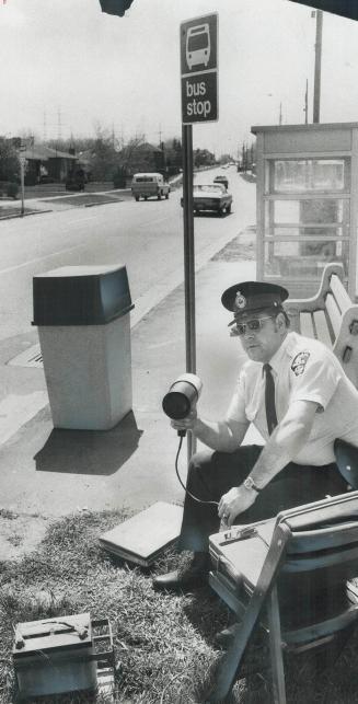 Waiting or a speeding bus?, Dispensing with a car, Oshawa Police Constable Fred Johns sets up shop at a bus stop on Bond St. E. with a folding chair, (...)