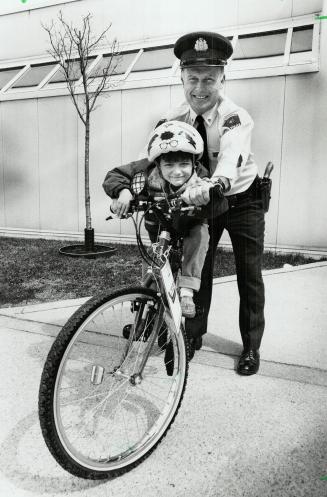 Training wheels: Randy Hutton, 5, practises his cycling technique with the help of steady-handed Peel Police Constable Ian Kittle at his side