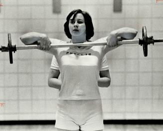 Staying in shape, Miss Phyllis works out with weights in the gymnasium