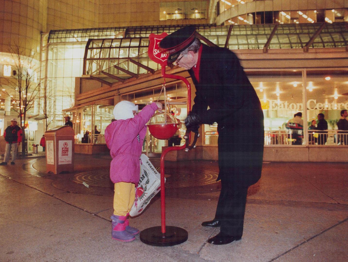 Soldier of charity: Major Hugh Tilley of the Salvation Army accepts a donation from a youngster outside the Eaton Centre