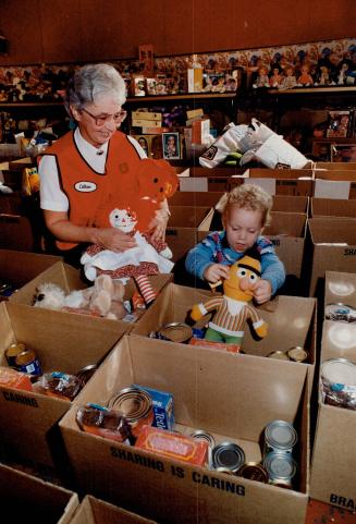 Santa's elves pack special Christmas hampers, Lil Kurtz watches Jason Young, 2, help pack food and toy packages at the Salvation Army's Christmas bure(...)