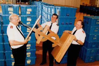 Salvation Army Lt.-Col.Clyde Moore, left, Commissioner Donald Kerr and Lt. Col. Mel Bond hoist furniture yesterday as the Sally Ann moves its downturn(...)