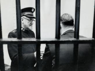 At the 'Bull Pen' in the old city hall, Salvation Army Brigadier Ernest Hutchinson gives aid and advice to accused before he's taken to magistrate's c(...)