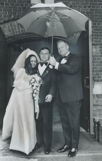 Police Chief Harold Adamson holds umbrella over his son, police constable Edward Adamson, and his new bride, the former Linda Daviduke, as they leave (...)