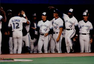 Some insurance: Roberto Alomar is congratulated in the dugout after his sacrifice fly drove in the Blue Jays' fifth run in the fourth inning