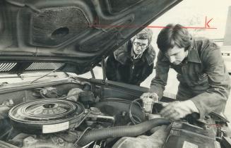 Pressure regulation is spliced into a car fuel line by Peter Coulter, watched by Star staff writer Marilyn Anderson, Gasoline consumption dropped by 2(...)