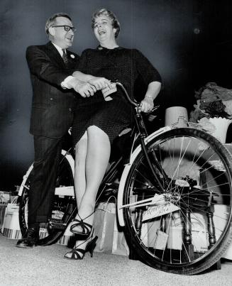 17,000 aid retarded children. Former controller William Archer and actress Barbara Hamilton try out bike, one of the prizes at 12th Annual Cocktail Pa(...)