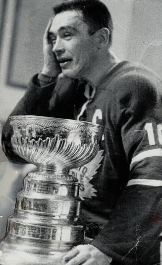 Happily stunned by victory, Maple Leaf winger George Armstrong leans on battered Stanley Cup in the Toronto dressing room. The Leafs captain collected(...)