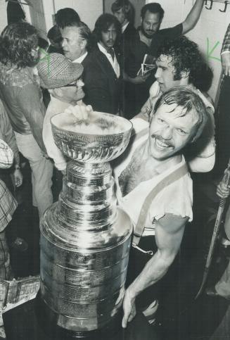 A delighted Bob Kelly, who potted winning goal in Flyers' 2-0 win, holds Stanley Cup in dressing room after last night's game. What a thrill, that goa(...)