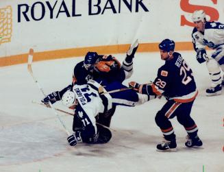 Bowled over: Leaf winger Mike Foligno salls past New York Islanders defenceman Joe Reekle and into goalie Steve Weeks during early action in last night's game at Maple Leaf Gardens