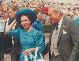 Royal race fan: Clad in a turquoise-blue silk dress and matching blue straw hat, Princess Margaret takes a stroll during her visit to Woodbine yesterday