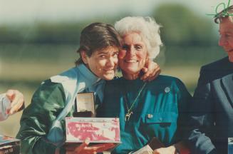 Jockey Cash Asmussen, who rode longshot Mill Native to victory in the Arlington Million race yesterday, hugs Carol Ray, wife of the horse's owner Corn(...)