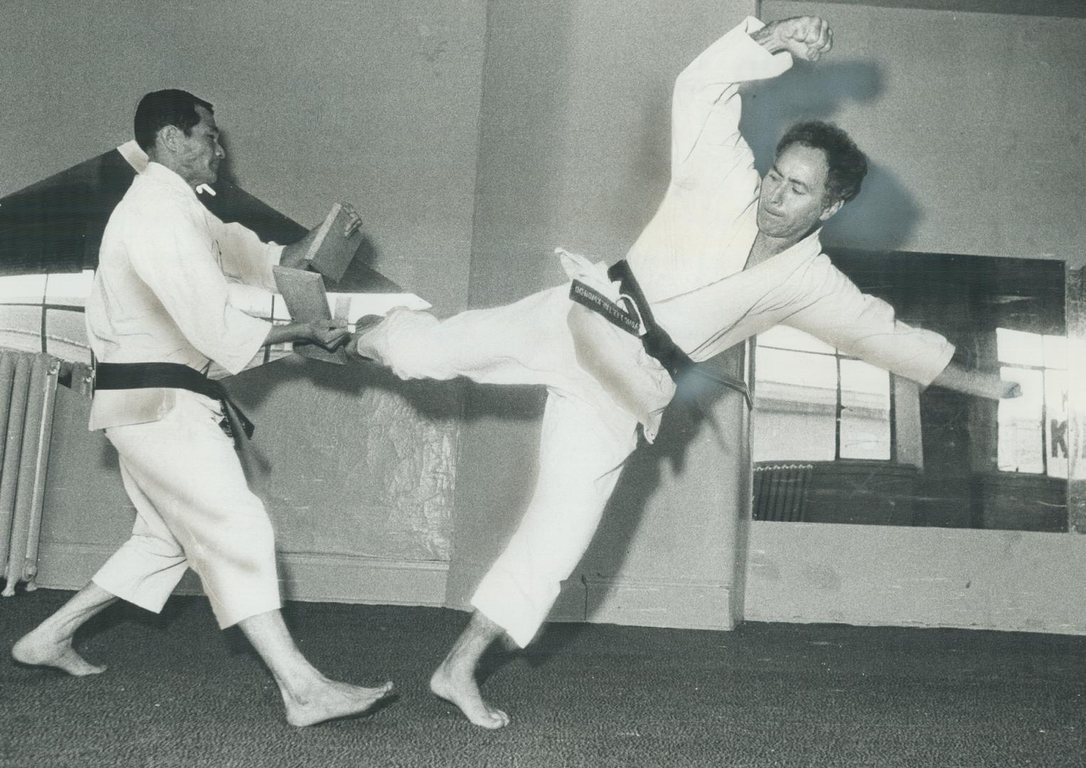Weingust, 42, uses his foot to break piece of wood held by karate instructor Kyong Lee