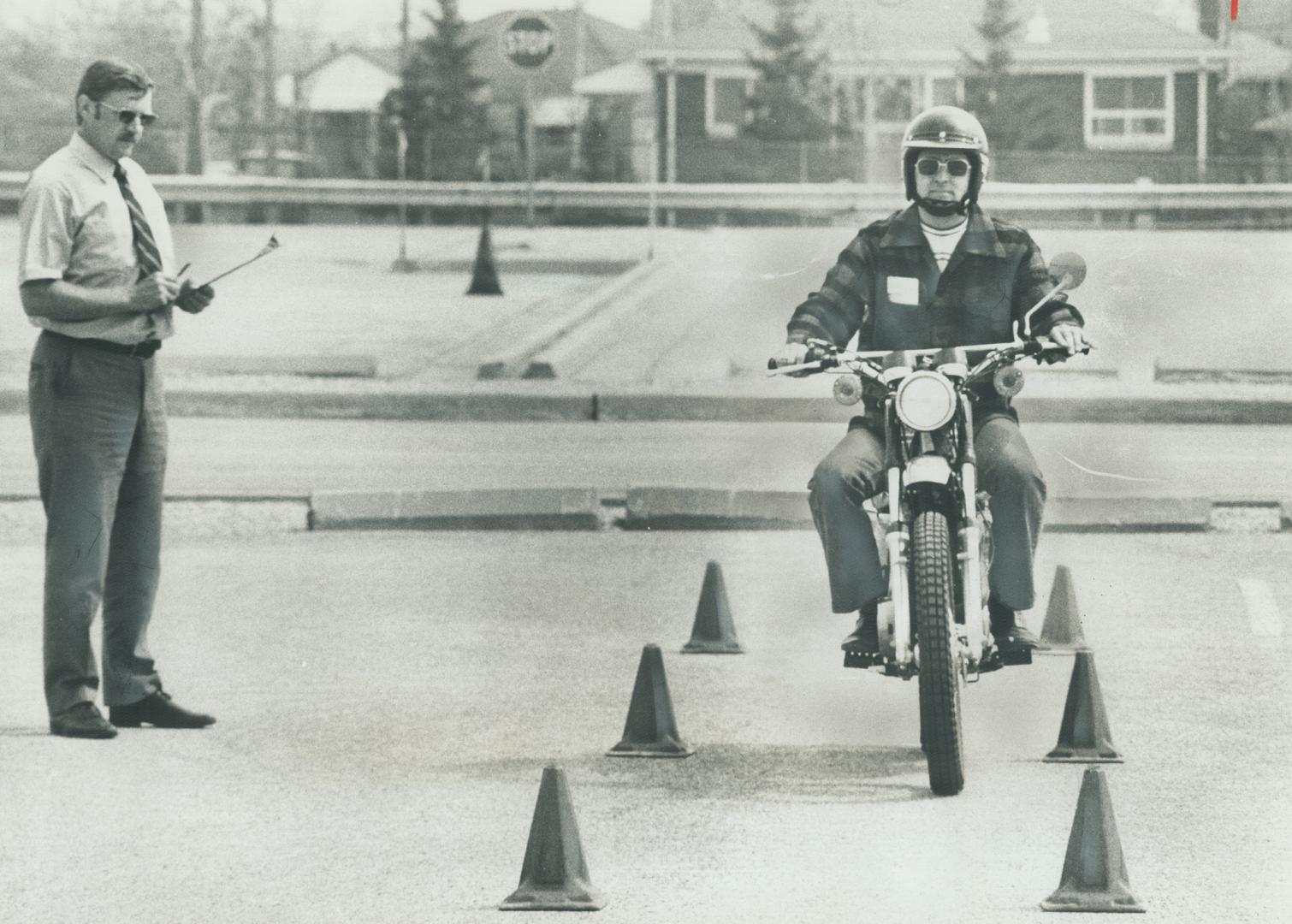 Driver examiner Fred Hanneman checks John King, as he manoeuvers his motorcycles around Department of Transportation and Communications test course at(...)