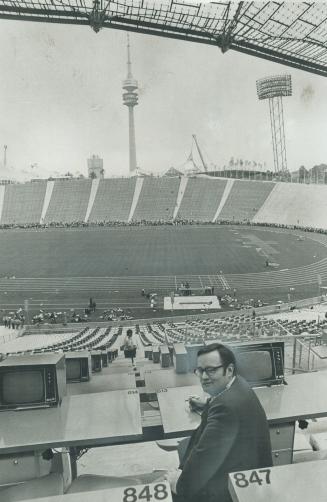 The star Sports Editor Jim Proudfoot sits in the 80,000-seat stadium, with the futuristic communications tower, the symbol of the 1972 Olympic Games, in background