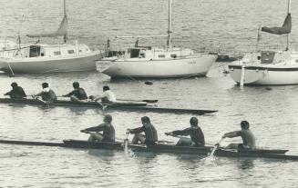 Lagoon near Argonaut Rowing Club on Lakeshore Blvd., four-man shells scull past moored sailing craft