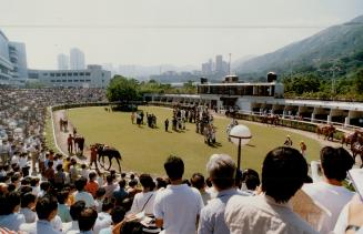 Race fans crowd the Sha Tin walking ring, near right, seeking the inside knowledge they use at the betting windows, far right. Below, King and colleag(...)