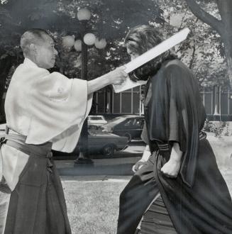 World's foremost karate master, Dr. Tsuyoshi Chitose, breaks one-inch board over head of Mamoru Yamomoto