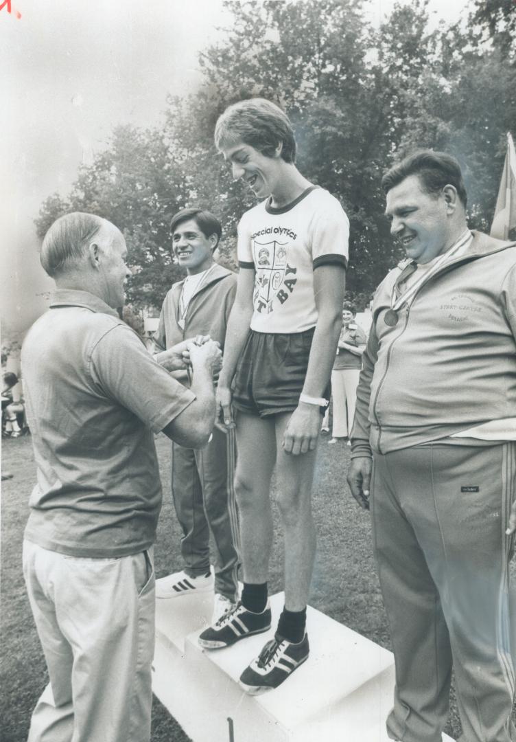 It's a hug for one winner, Dan Lalonde, 19, of North Bay, accepts medal for winning 50-metre senior race from Murray Scott