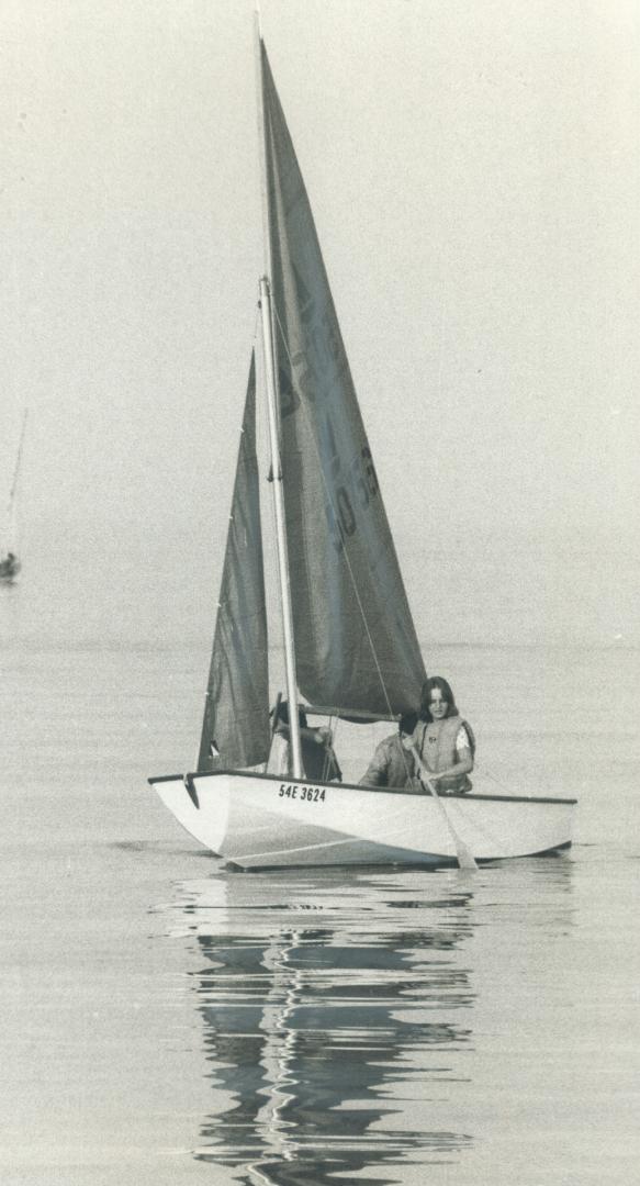 A mirror on Lake Ontario, Small sailboats ran out of wind off Bronte Harbor, and their sails idly slapping from side to side cast long, wavy reflectio(...)