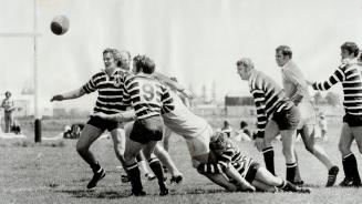 It's Anybody's Ball at Fletcher Field, Touring English rugby team from Somerset (striped shirts) have situation well in hand as ball squirts loose dur(...)