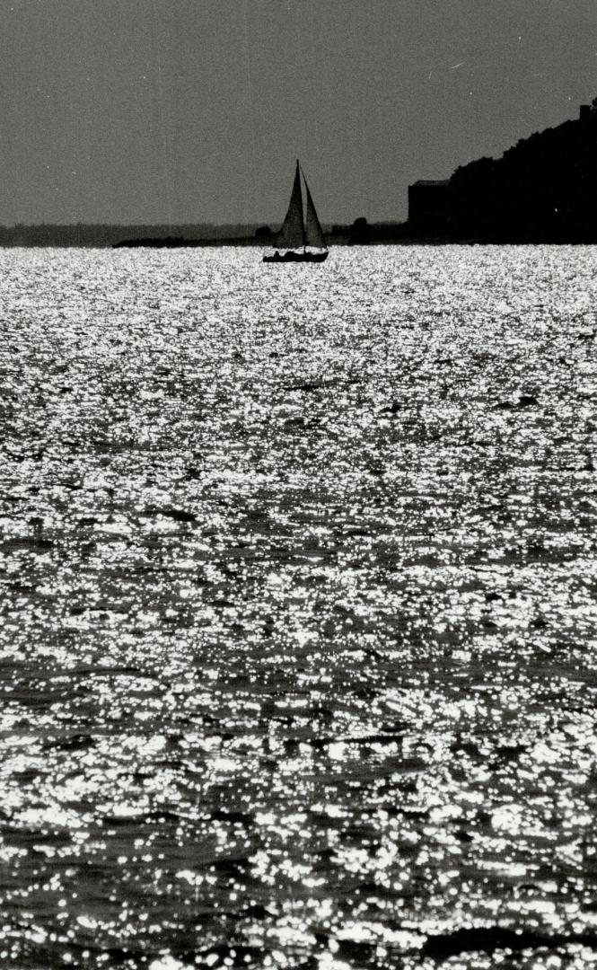 The season sails on, A lone sailboat glides across the tranquil waters of Lake Ontario near Scarborough's Bluffers Park