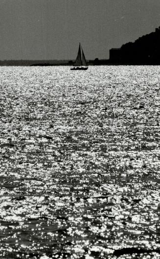 The season sails on, A lone sailboat glides across the tranquil waters of Lake Ontario near Scarborough's Bluffers Park