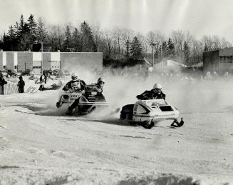 Competing for cups and money, snowmobiles race around a track on trucked-in snow at the Sno-brr-fest in Orangeville
