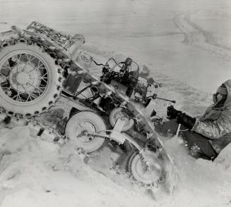 Charging a steep bank of snow on the shore of James Bay, George Bettes shows how his caterpillar-equipped snowmobile can take the grades. This is the (...)