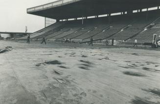 CNE workmen begin peeling back a soggy tarpanlin at the stadium this morning in preparation for this afternoon's eastern conference final between the (...)