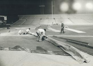 Workmen roll down the artificial turf at Toronto's Canadian National Exhibition stadium, which has 160,396 square feet of it. The stadium manager says(...)