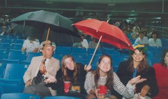 Oh no, it leaks: Umbrellas come in handy last night at the SkyDome opening, when roof leaked even before it was opened to a drenching rain