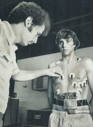 A fitness therapist at the Etobicoke Olympium wires speed swimmer Bill Bevan to a $27,000 analytical computer that evaluates physical conditions. Beva(...)