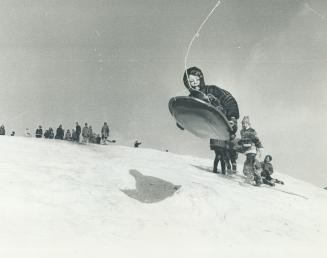 Boy on Toboggan (left) is airborne after he hit a three-foot depression in the snow that blankets a hill 100 feet high made from fill in Centrel Park,(...)