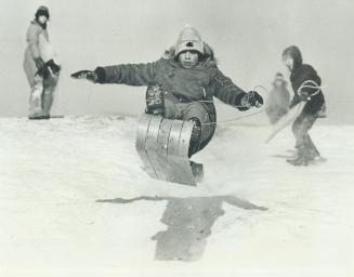Boy on Toboggan (left) is airborne after he hit a three-foot depression in the snow that blankets a hill 100 feet high made from fill in Central Park,(...)