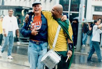 Good sports: A Brazil fan, right, shows there are no hard feelings as he embraces a Dutch supporter follwing yesterday's World Cup semifinal game