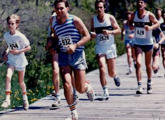 Savoring the sunshine, runners in Sport Aid's Race Against Time pound along a board walk on Centre Island yesterday