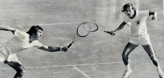 All together now! The Spanish doubles pair of Manuel Orantes (left) and Antonio Munoz react at the same instant to volley tossed up by their opponents(...)