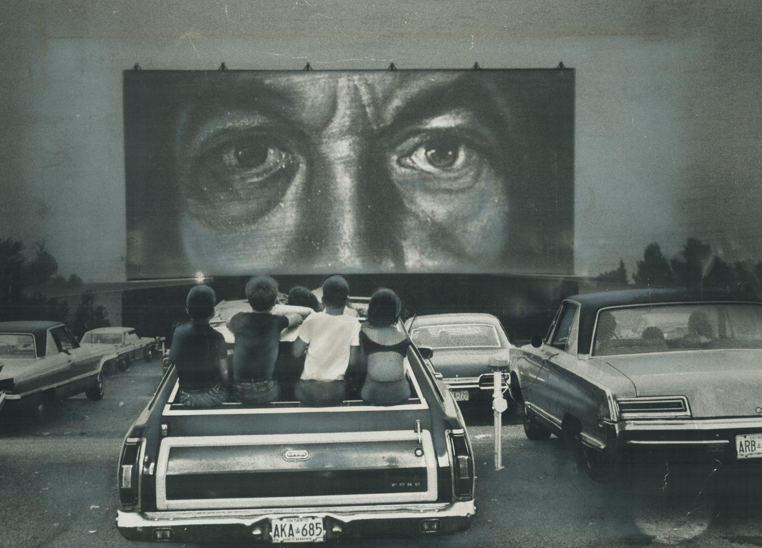 A Night out at the drive-in. These children watch from station wagon as parents take in a drive-in movie. Drive-ins are attracting family audiences, s(...)