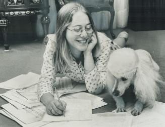 Young Toronto song-writer and recording artist Carol Lipson, With her pet poodle watching, she sprawls on the living-room floor working on her music