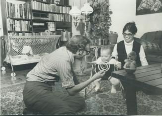 Television producer Jerry Lawton plays with his son, Mikael, 5 months, while his wife, Inger, watches