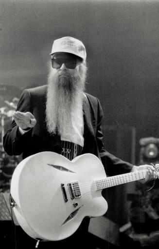 Hairy Godfather of Rock: Billy Gibbons looks sultably goofy in sunglasses, black suit, white guitar, pink baseball cap and two-foot-long beard, at Maple Leaf Gardens