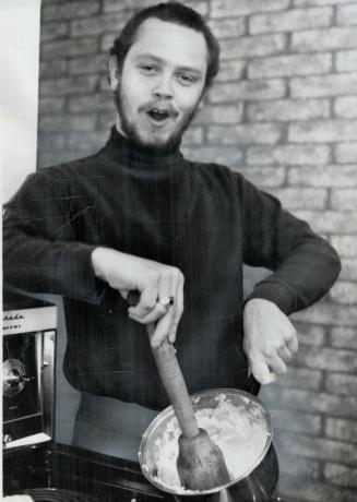 George Millar mashes potatoes. Member of the pop group, he lightens chore with song