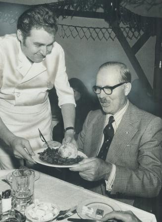 Mayor William Dennison is ready to enjoy a meal of wild boar, potato dumplings and red cabbage served by chef Klaus Theyer, left. Other traditional Ok(...)