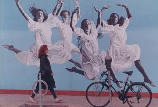 A woman walks past a giant mural painted on the wall of the Canadian Children's Dance Theatre at 509 Parliament St