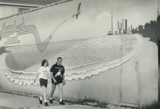 A beach built for two. Rhoda Bruce and Eric Abrahams enjoy yesterday's summer-like weather as they stroll past a mural of the city shoreline on Cherry(...)