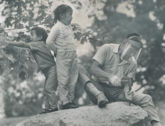 Children romp while dad, eskimo sculptor Pauta - who is from cae dorset - works in high park